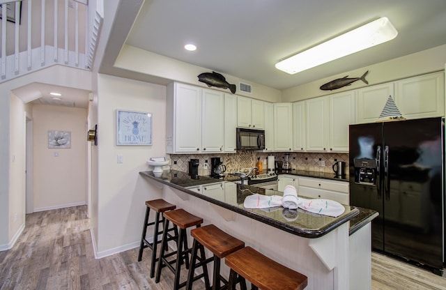 16713 Kingston Way, Jamaica Beach, TX 77554 - kitchen featuring black appliances, backsplash, a breakfast bar area, light wood-style floors, and recessed lighting