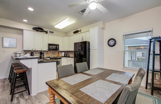 16713 Kingston Way, Jamaica Beach, TX 77554 - kitchen featuring black appliances, a peninsula, decorative backsplash, dark countertops, and white cabinetry