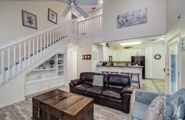 16713 Kingston Way, Jamaica Beach, TX 77554 - living room with a high ceiling, a ceiling fan, stairs, and light wood-style flooring