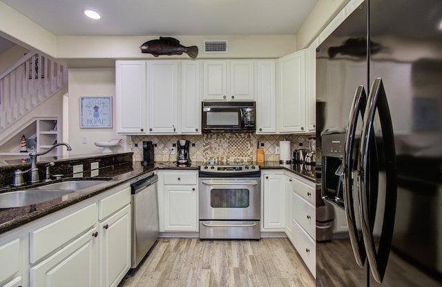 16713 Kingston Way, Jamaica Beach, TX 77554 - kitchen featuring black appliances, light wood finished floors, decorative backsplash, white cabinets, and dark stone counters