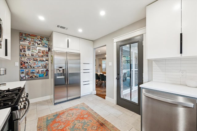 6210 Darnell St, Houston, TX 77074 - kitchen with appliances with stainless steel finishes, light countertops, white cabinets, backsplash, and light tile patterned floors