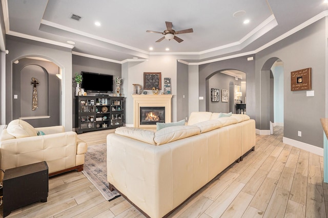 3038 S Island Dr, Seabrook, TX 77586 - living area with a tray ceiling, ceiling fan, arched walkways, light wood-type flooring, and a glass covered fireplace