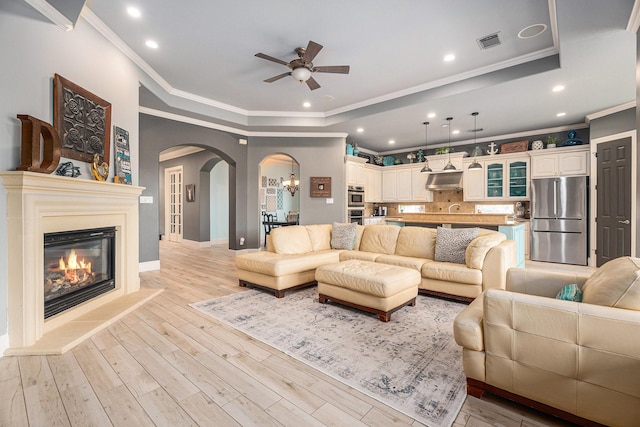 3038 S Island Dr, Seabrook, TX 77586 - living room with a raised ceiling, ceiling fan, arched walkways, crown molding, and light wood finished floors