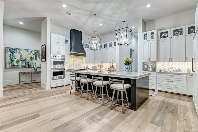 4622 Banning Dr, Houston, TX 77027 - kitchen featuring custom exhaust hood, double oven, tasteful backsplash, a breakfast bar, and recessed lighting
