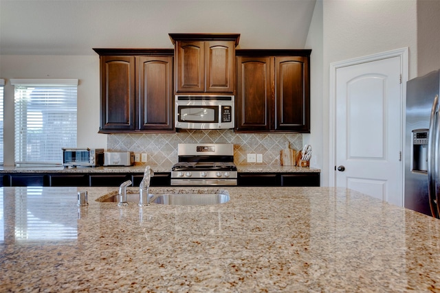 2407 Lost Bridge Ln, Pearland, TX 77584 - kitchen with stainless steel appliances, backsplash, light stone counters, and dark brown cabinetry