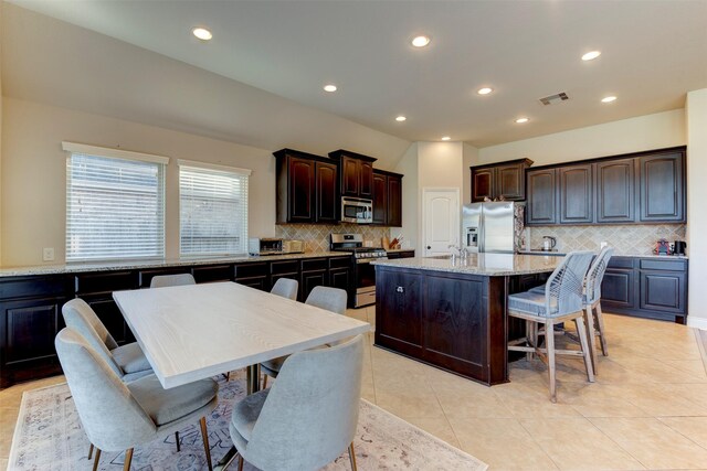 2407 Lost Bridge Ln, Pearland, TX 77584 - kitchen featuring appliances with stainless steel finishes, tasteful backsplash, a center island with sink, dark brown cabinets, and recessed lighting