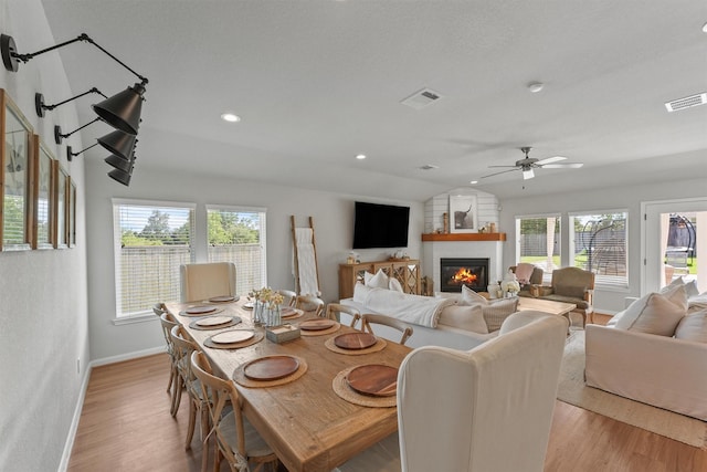 2307 Hagerman Rd, Conroe, TX 77384 - dining area with a ceiling fan, light wood finished floors, vaulted ceiling, a fireplace, and recessed lighting