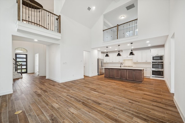 17471 Bayflower, Conroe, TX 77385 - unfurnished living room featuring a towering ceiling, stairs, and wood finished floors