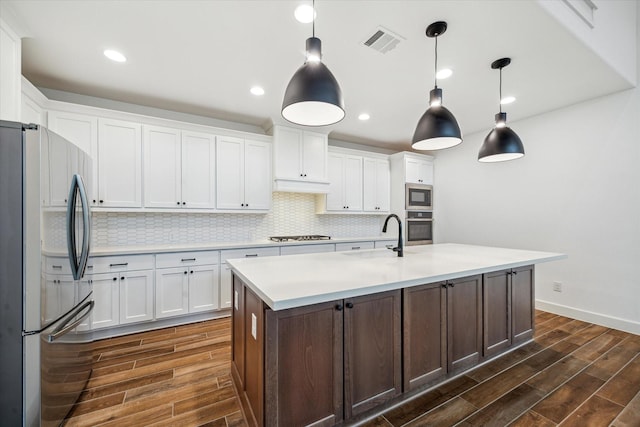 17471 Bayflower, Conroe, TX 77385 - kitchen with appliances with stainless steel finishes, dark wood-style floors, backsplash, light countertops, and white cabinets