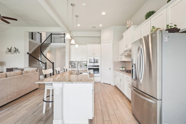29446 Westhope Dr, Spring, TX 77386 - kitchen featuring appliances with stainless steel finishes, a ceiling fan, open floor plan, light wood-style floors, and recessed lighting