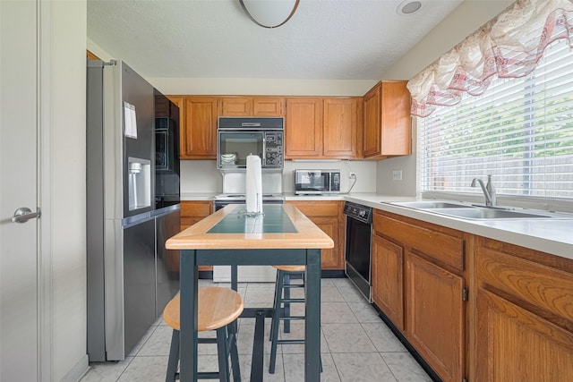 7838 Poitiers Dr, Houston, TX 77071 - kitchen featuring black appliances, light countertops, brown cabinets, and a textured ceiling