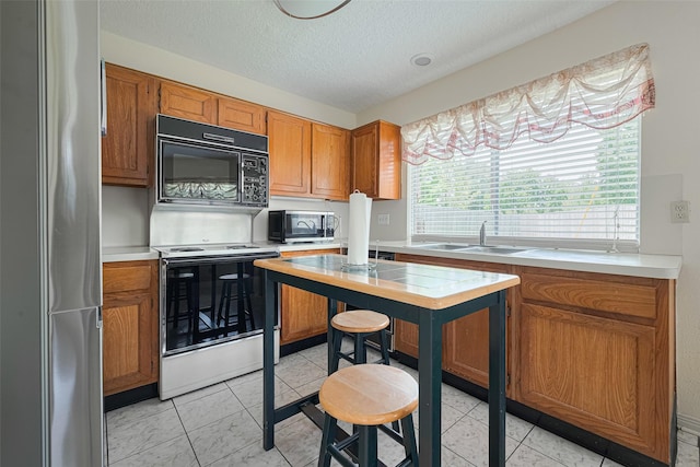 7838 Poitiers Dr, Houston, TX 77071 - kitchen featuring appliances with stainless steel finishes, light countertops, brown cabinets, and a textured ceiling