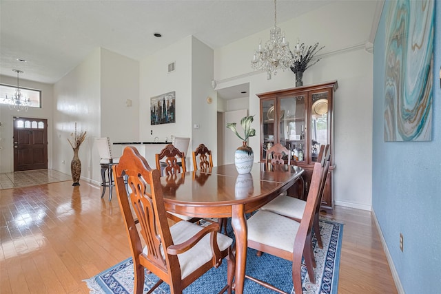 7838 Poitiers Dr, Houston, TX 77071 - dining space with a chandelier, light wood-style floors, and a towering ceiling