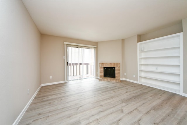 12905 Woodforest Blvd Unit 202, Houston, TX 77015 - unfurnished living room with light wood-type flooring, a brick fireplace, and built in shelves