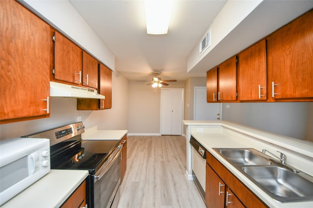 12905 Woodforest Blvd Unit 202, Houston, TX 77015 - kitchen with under cabinet range hood, white appliances, ceiling fan, light wood-style flooring, and brown cabinets