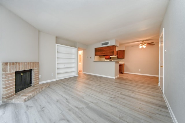 12905 Woodforest Blvd Unit 202, Houston, TX 77015 - unfurnished living room featuring ceiling fan, a brick fireplace, light wood finished floors, and built in shelves