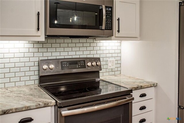 248 Park Rd, Port Lavaca, TX 77979 - kitchen with range with electric cooktop, stainless steel microwave, backsplash, and white cabinetry