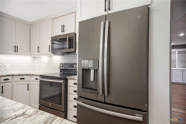 248 Park Rd, Port Lavaca, TX 77979 - kitchen featuring stainless steel appliances, light stone countertops, decorative backsplash, wood finished floors, and white cabinetry