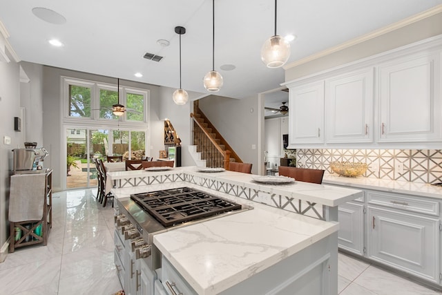 8706 Ashridge Park Dr, Spring, TX 77379 - kitchen with a ceiling fan, a center island, stainless steel gas stovetop, backsplash, and light marble finish floors