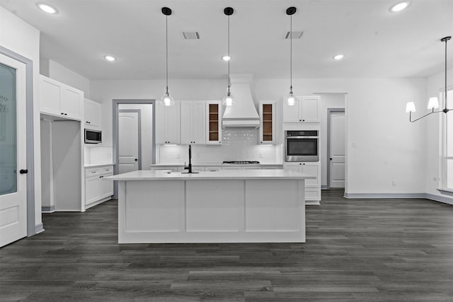 29 Westwood Dr W, Trinity, TX 75862 - kitchen with stainless steel appliances, custom exhaust hood, white cabinetry, backsplash, and dark wood-style flooring