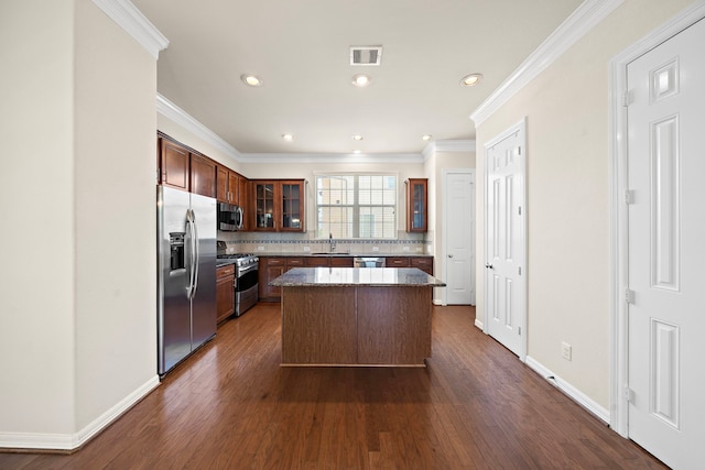878 Fisher St, Houston, TX 77018 - kitchen with appliances with stainless steel finishes, ornamental molding, dark wood-style floors, a kitchen island, and glass insert cabinets