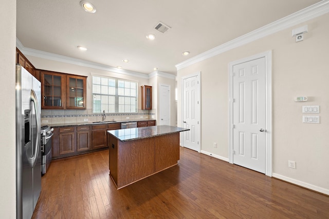 878 Fisher St, Houston, TX 77018 - kitchen with appliances with stainless steel finishes, a center island, ornamental molding, backsplash, and dark wood-type flooring