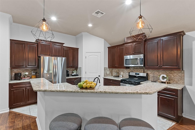 4202 Carnes Ct S, College Station, TX 77845 - kitchen featuring appliances with stainless steel finishes, hanging light fixtures, a kitchen island with sink, light wood-style floors, and recessed lighting