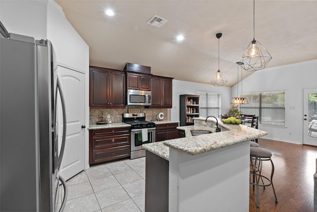 4202 Carnes Ct S, College Station, TX 77845 - kitchen with appliances with stainless steel finishes, tasteful backsplash, a breakfast bar, hanging light fixtures, and lofted ceiling