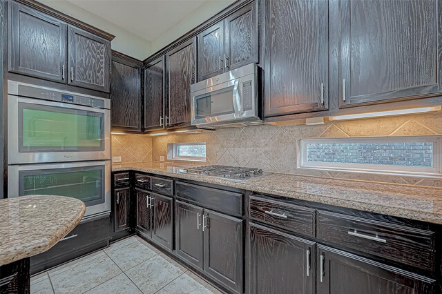 30806 Academy Trace Dr, Spring, TX 77386 - kitchen featuring appliances with stainless steel finishes, decorative backsplash, light tile patterned flooring, and light stone counters