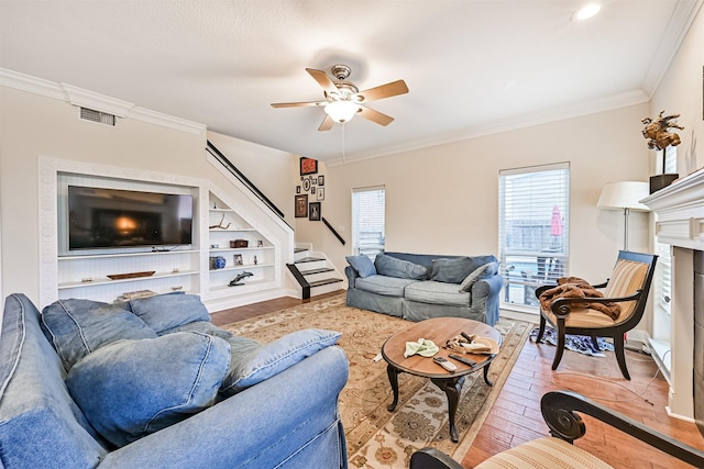 12811 E Conquistador, Galveston, TX 77554 - living area with ornamental molding, a ceiling fan, light wood-style flooring, stairs, and a fireplace