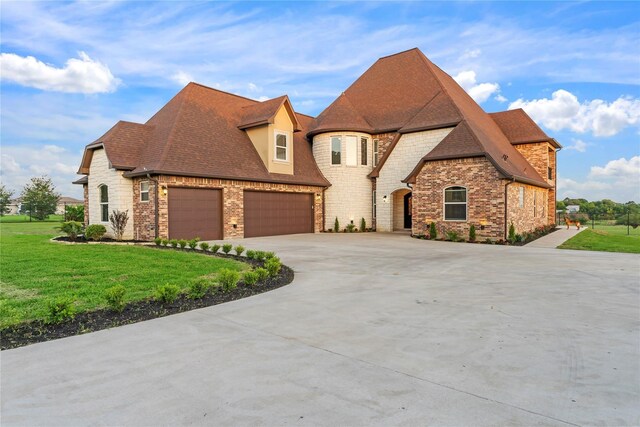 2830 Airport Rd, Brenham, TX 77833 - french country home with a garage, concrete driveway, a front yard, a shingled roof, and stone siding