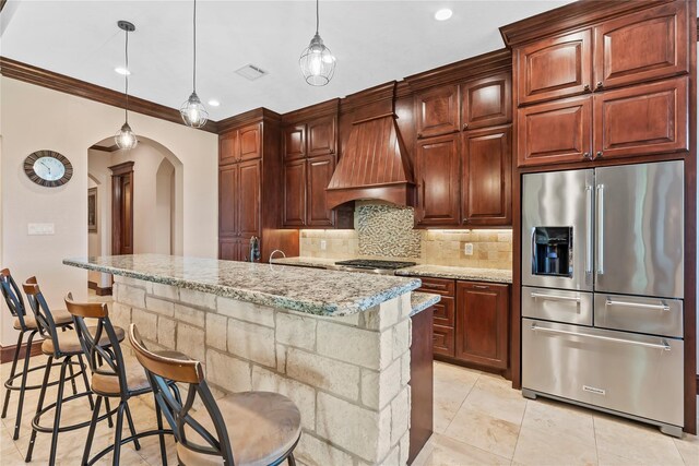 2830 Airport Rd, Brenham, TX 77833 - kitchen with high end refrigerator, custom exhaust hood, arched walkways, backsplash, and a center island with sink