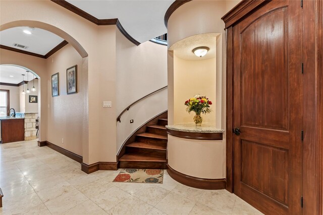 2830 Airport Rd, Brenham, TX 77833 - entryway featuring crown molding, arched walkways, stairway, and light tile patterned flooring