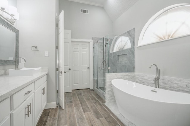 6302 Laver Love Dr, Spring, TX 77379 - bathroom featuring vanity, a soaking tub, a stall shower, vaulted ceiling, and wood finished floors