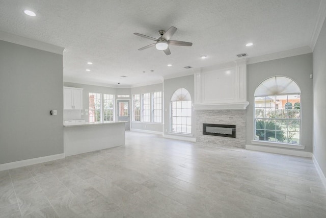 6302 Laver Love Dr, Spring, TX 77379 - unfurnished living room featuring ornamental molding, ceiling fan, a stone fireplace, recessed lighting, and a textured ceiling