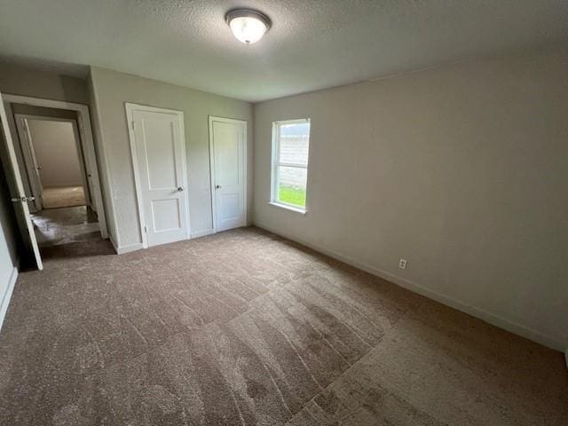2227 Westway St, Orange, TX 77630 - unfurnished bedroom with a textured ceiling, carpet flooring, and multiple closets