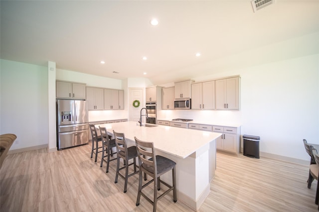 127 Dorado Dr, Friendswood, TX 77546 - kitchen with appliances with stainless steel finishes, a kitchen breakfast bar, an island with sink, light wood finished floors, and light countertops