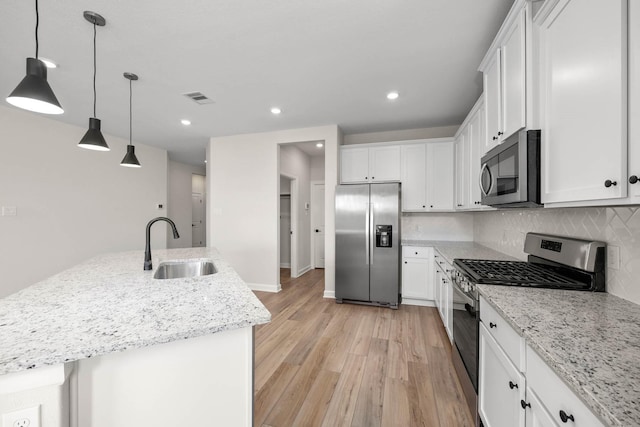 3004 Myrtle Sunset Dr, Katy, TX 77493 - kitchen with stainless steel appliances, light wood-style flooring, white cabinets, backsplash, and light stone counters