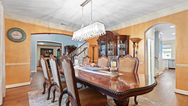 37703 Edgewater Dr, Pinehurst, TX 77362 - dining space featuring arched walkways, stairway, hardwood / wood-style floors, and crown molding