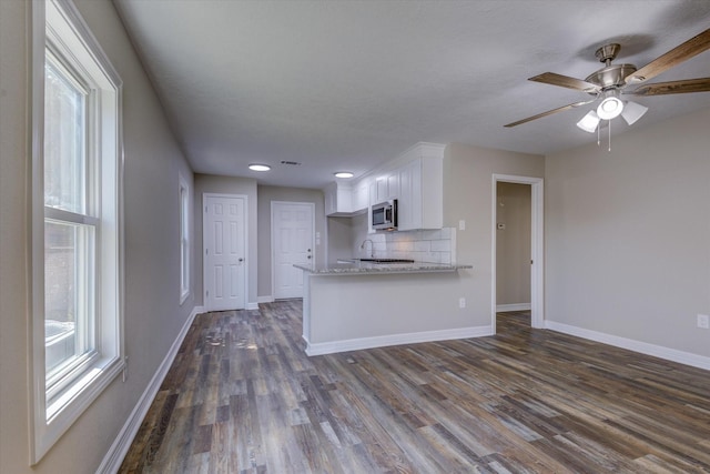 3802 Ranch St, Houston, TX 77026 - kitchen with stainless steel microwave, white cabinets, dark wood-style flooring, backsplash, and light stone countertops