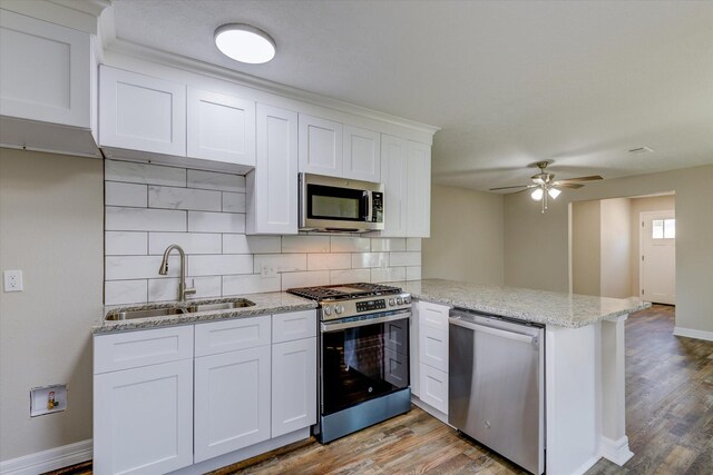 3802 Ranch St, Houston, TX 77026 - kitchen with stainless steel appliances, a peninsula, tasteful backsplash, light wood-style floors, and white cabinets