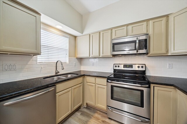 3200 Bellefontaine St Unit 72, Houston, TX 77025 - kitchen with appliances with stainless steel finishes, cream cabinets, light wood-style flooring, and tasteful backsplash