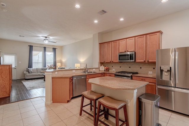 2954 Smokey Forest Ln, Spring, TX 77386 - kitchen with appliances with stainless steel finishes, a peninsula, light countertops, decorative backsplash, and light tile patterned floors