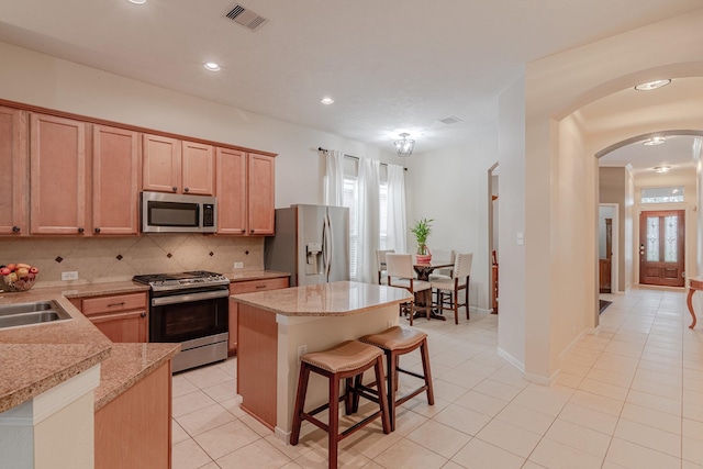 2954 Smokey Forest Ln, Spring, TX 77386 - kitchen featuring appliances with stainless steel finishes, arched walkways, backsplash, a kitchen island, and a kitchen bar