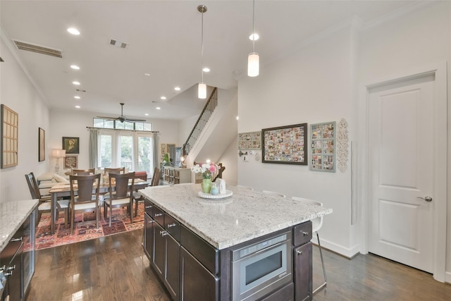 3937 Law St, Houston, TX 77005 - kitchen featuring crown molding, dark wood finished floors, recessed lighting, a center island, and stainless steel microwave