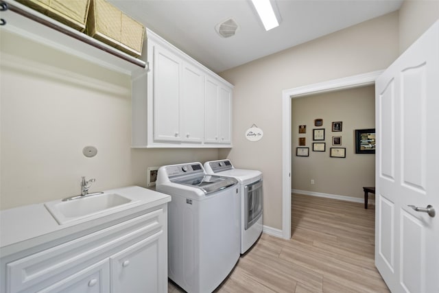 18882 Mystic Pt, Montgomery, TX 77356 - washroom with washer and clothes dryer, cabinet space, and light wood-type flooring