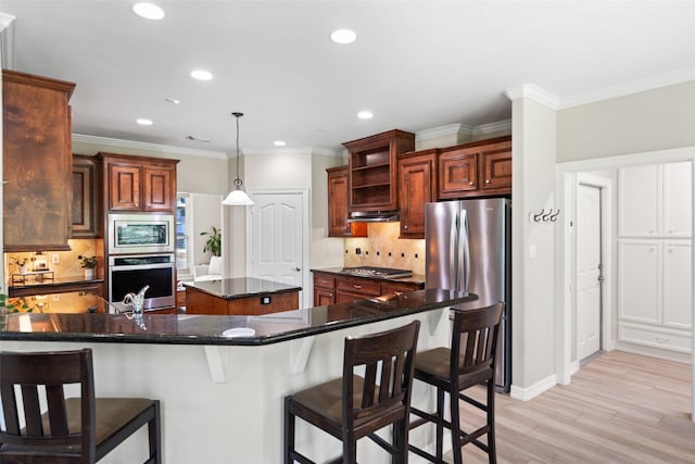 18882 Mystic Pt, Montgomery, TX 77356 - kitchen featuring appliances with stainless steel finishes, a center island, recessed lighting, light wood finished floors, and backsplash