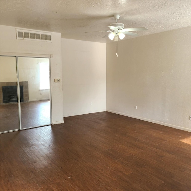 2021 Spenwick Dr Unit 511, Houston, TX 77055 - unfurnished room with a ceiling fan, wood finished floors, a tiled fireplace, and a textured ceiling