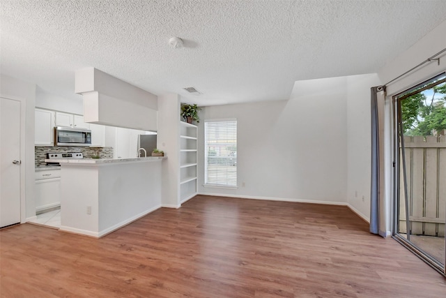 2120 El Paseo St Unit 501, Houston, TX 77054 - kitchen with stainless steel appliances, light wood-type flooring, a textured ceiling, white cabinets, and light countertops