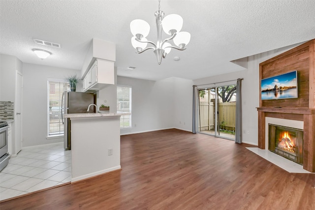 2120 El Paseo St Unit 501, Houston, TX 77054 - kitchen featuring a textured ceiling, light countertops, a chandelier, white cabinets, and a fireplace with flush hearth